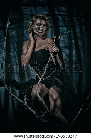 Portrait of a retro woman with skull make-up in the night forest