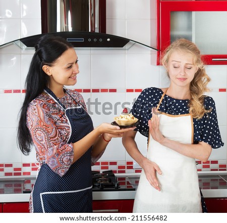 Smiling woman giving a homemade cake to the girl obsessed with counting calories