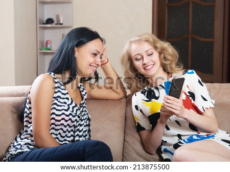 Woman talks about something to her friend and pointing at the cell phone