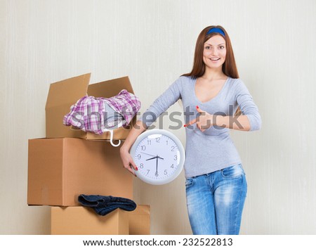 Smiling woman pointing at the clock with the moving boxes
