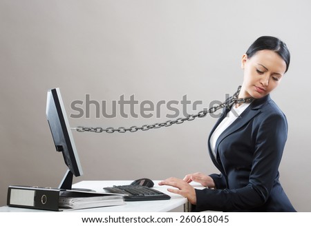 Female office worker chained to her computer