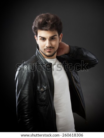 Man in white T-shirt and black leather jacket looking at camera