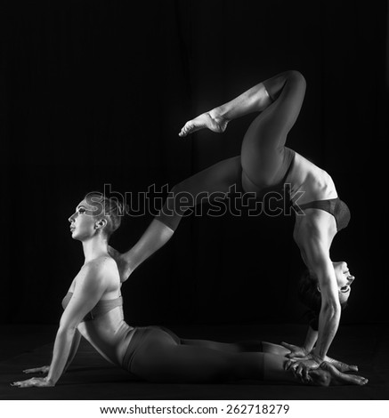 Two women practicing gymnastic yoga, black and white studio shot