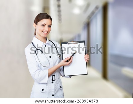 Portrait of a smiling nurse pointing to clipboard