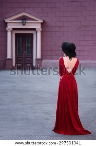 Full length portrait of a lady in long red dress, back view