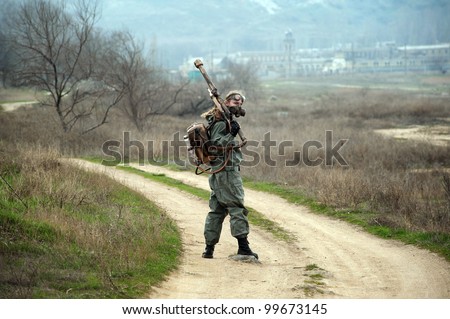 Stalker soldier with chemical armor and the flame gun staying on the road looking back.