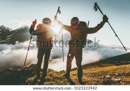 Happy travel couple man and woman on mountain summit love and adventure hiking Lifestyle wanderlust concept sunset light
