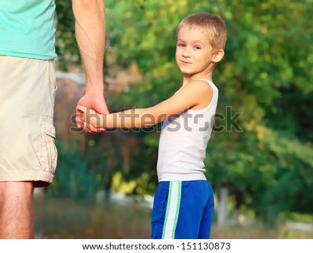 Happy Family Father Man and Son Boy Child holding hand in hand Outdoor with summer nature on background