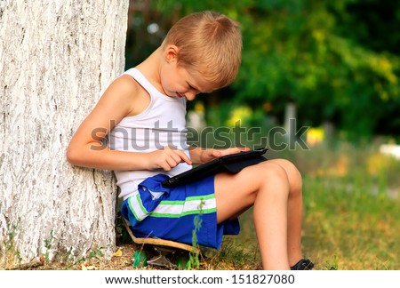 Boy Child playing with Tablet PC Outdoor with forest on background Computer Game Dependence concept