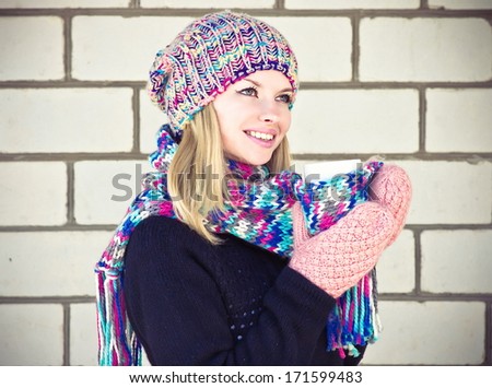 Winter Woman happy smiling Face with coffee cup wearing knitted sweater, hat and scarf with mittens Lifestyle concept with white brick wall on background