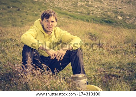 Man relaxing in mountains sitting on grass valley with pot cooking Traveling hiking summer recreation