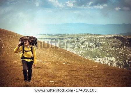 Man Traveler with Backpack hiking in Mountains Survival into the wild