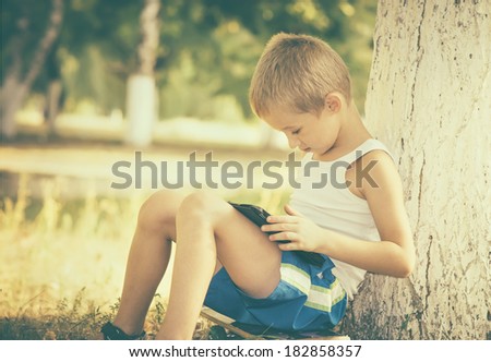 Boy Child playing with Tablet PC Outdoor with Summer nature on background Computer Game Dependence concept Lifestyle retro colors