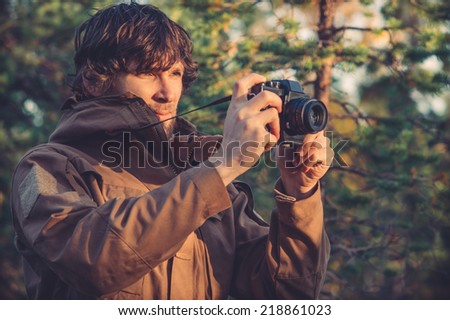 Young Man with retro photo camera outdoor hipster Lifestyle forest nature on background