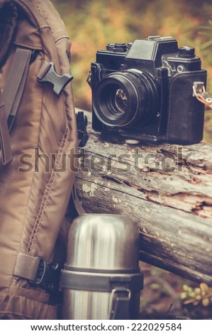 Lifestyle hiking camping equipment retro photo camera backpack and thermos outdoor forest nature on background