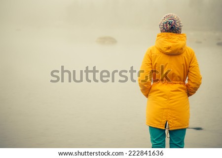 Young Woman standing alone outdoor Travel Lifestyle and melancholy emotions concept  winter foggy nature on background