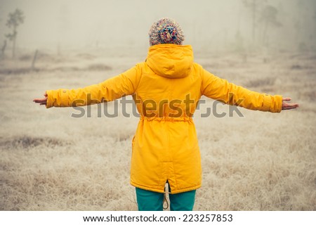 Young Woman with raised hands enjoying outdoor Travel Lifestyle and happiness emotions concept  winter foggy nature on background