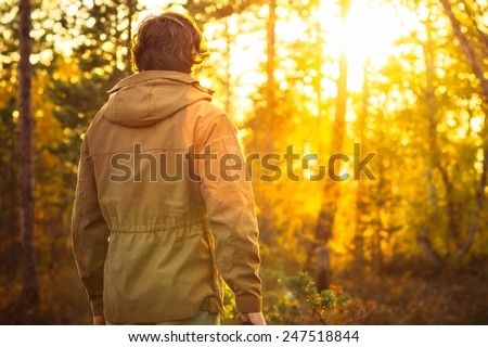 Young Man standing alone in forest outdoor with sunset nature on background Travel Lifestyle and survival concept