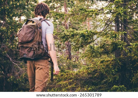 Young Man hiking in forest with backpack Travel Lifestyle and outdoor recreation summer vacations concept