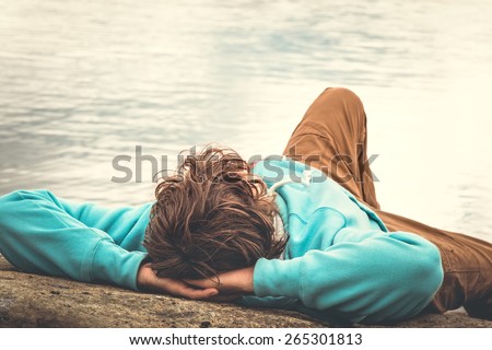 Young Man laying relaxing outdoor with lake on background Lifestyle Travel concept