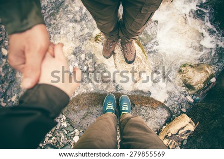 Feet Couple Man and Women in love holding hands hiking outdoor Lifestyle Travel and relationship concept river and stones on background top view