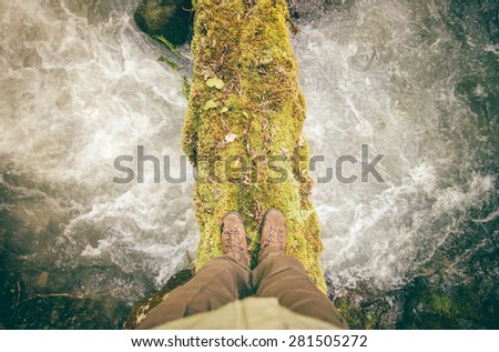 Feet Man trekking boots hiking outdoor with river and stones on background Lifestyle Travel survival concept top view