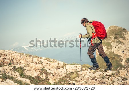 Young Man with backpack and trekking poles running outdoor Travel Lifestyle hiking concept rocky mountains on background Summer vacations