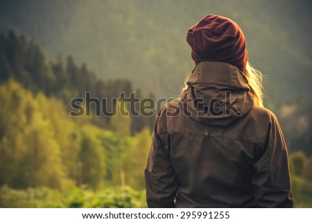 Young Woman standing alone outdoor with wild forest mountains on background Travel Lifestyle and survival concept rear view