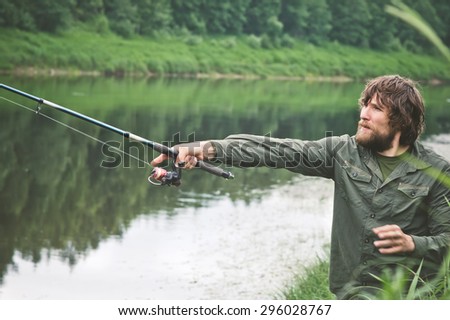 Young Man Fisherman bearded fishing with rod Lifestyle Travel survival concept river on background
