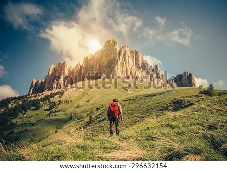 Young Man with backpack relaxing outdoor Travel Lifestyle hiking concept with rocky mountains on background Summer vacations