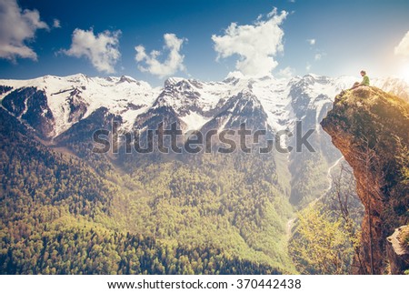 Young Man relaxing on mountain cliff outdoor with mountains on background Lifestyle Travel concept Summer vacations