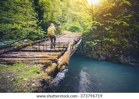 Woman Traveler with backpack hiking on bridge over river Travel Lifestyle concept forest on background Summer journey vacations outdoor