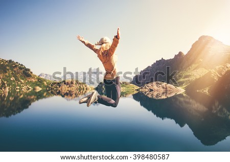 Happy Woman jumping up Flying levitation with lake and mountains on background Lifestyle Travel emotions concept outdoor