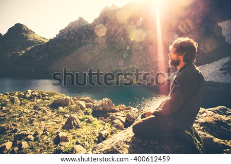 Bearded Man meditating relaxing alone Travel healthy Lifestyle concept lake and mountains sunny landscape on background outdoor