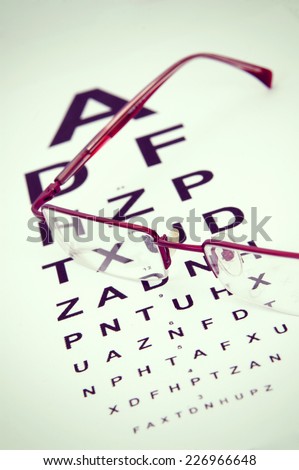 a pair of black reading glasses on top of an eye test chart