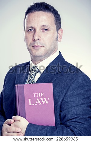 Senior Lawyer in his suit holding a red code of law in his hand.