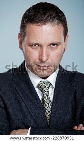 A man in a black suit sneering/smirking in a nasty way