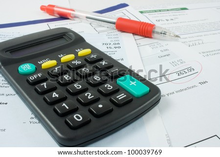 calculator and a red ballpoint pen sitting on bank statements