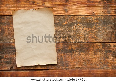 close up of an old worn blank piece of paper with burnt and torn edges, nailed to an old weathered plank door