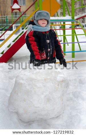 child on street plays with snow