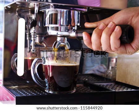 espresso machine with hand in processing coffee drink