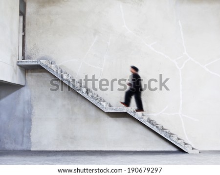 man walking on stairs to the door on cement wall background