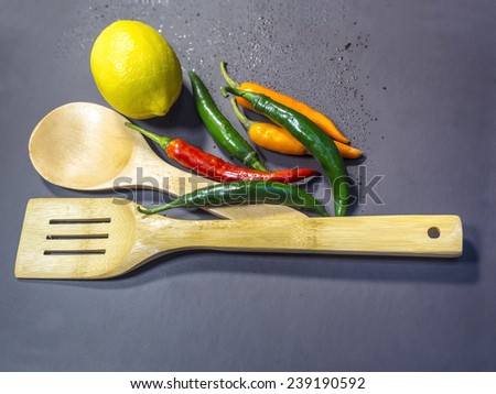 lemon chili and bamboo spoon on grey background