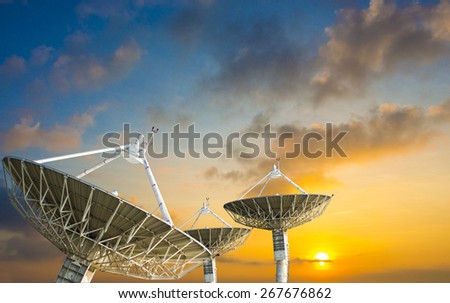 Satellite dish receiving data signal for communication, on colorful sunset sky