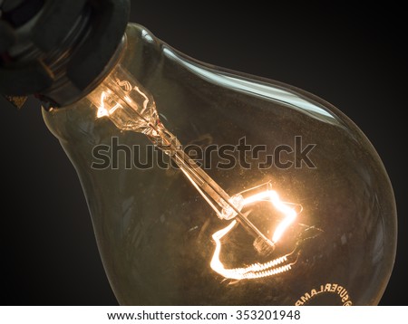 close up of glowing element in the incandescent light bulb, showing hot wire glow by electric current flowing in the tungsten filament