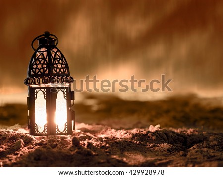 lantern lighted inside by candle and shining on sand floor playground, children play with it in Ramadan night, also known and called as Ramadan lantern