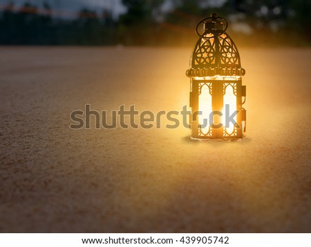 lighting with candle inside Lantern shining on sand floor playground, children play with it in Ramadan night, also known and called as Ramadan Kareem Lantern