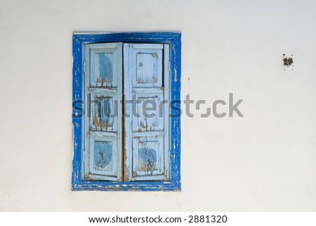 White wall with blue old window with sun blinds