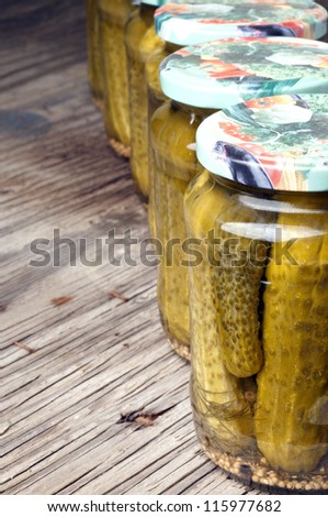 Glass jars with pickled cucumber on wood