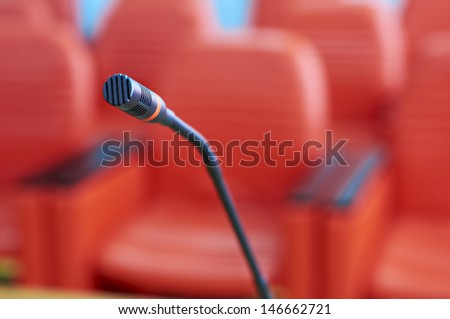 before a conference, the microphone in front of empty chairs.